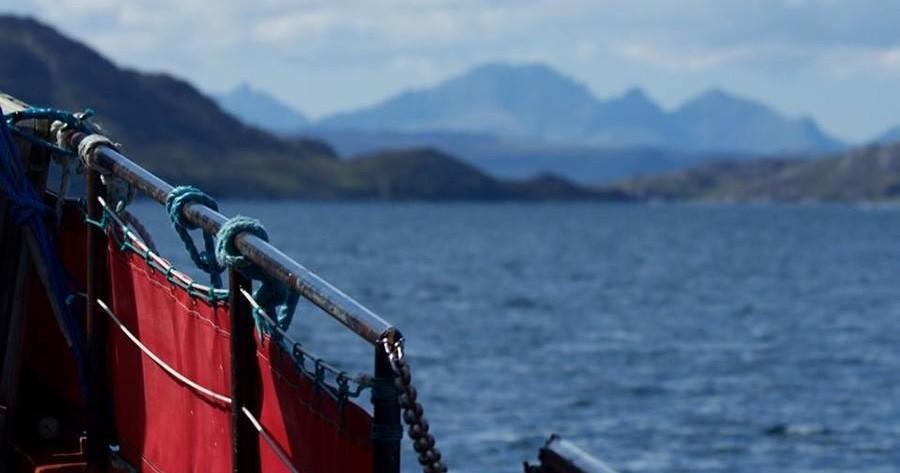 Red boat railing with mountain and lake view in the background.