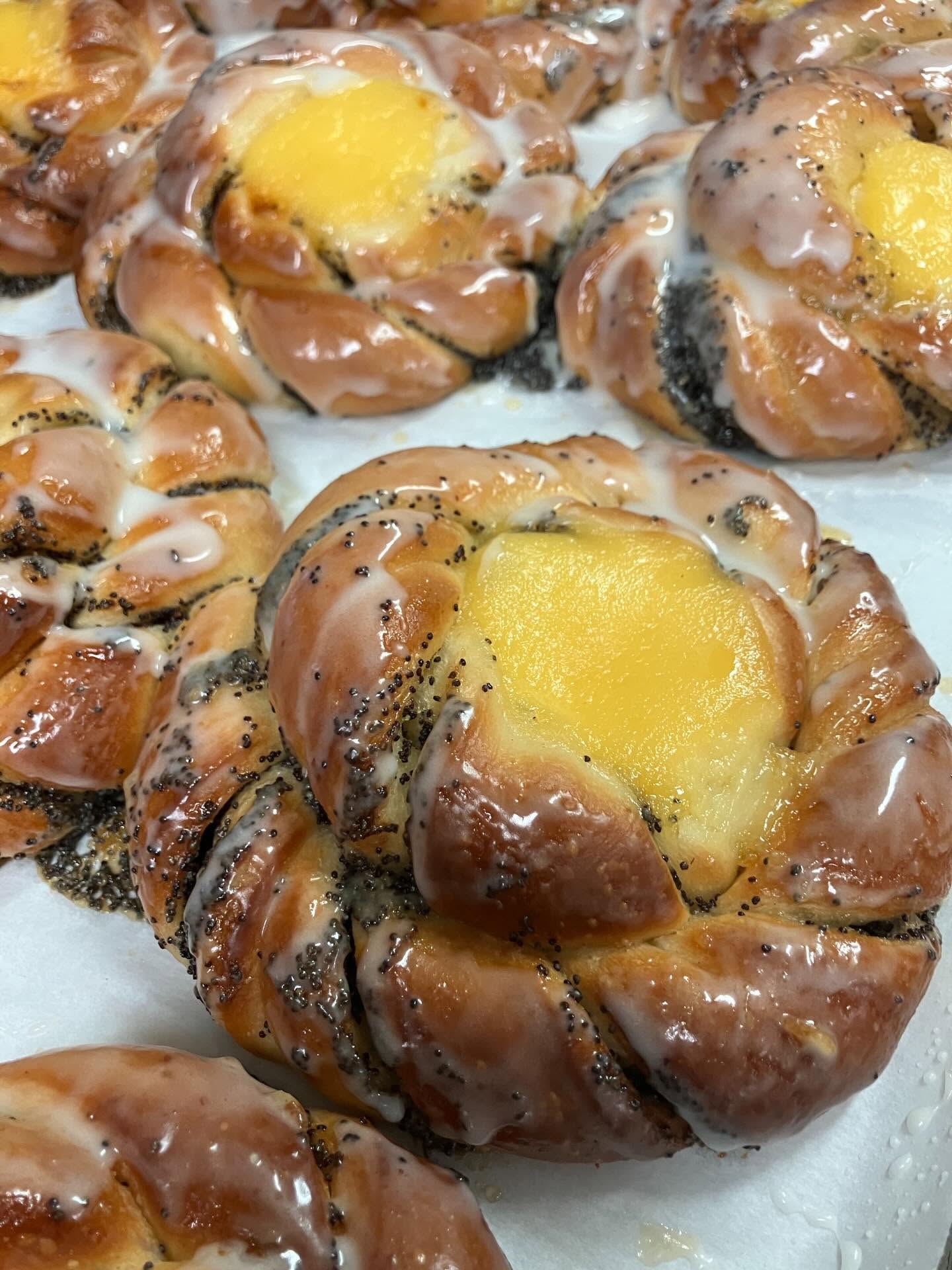 Close-up of glazed pastries with yellow custard center and poppy seeds.