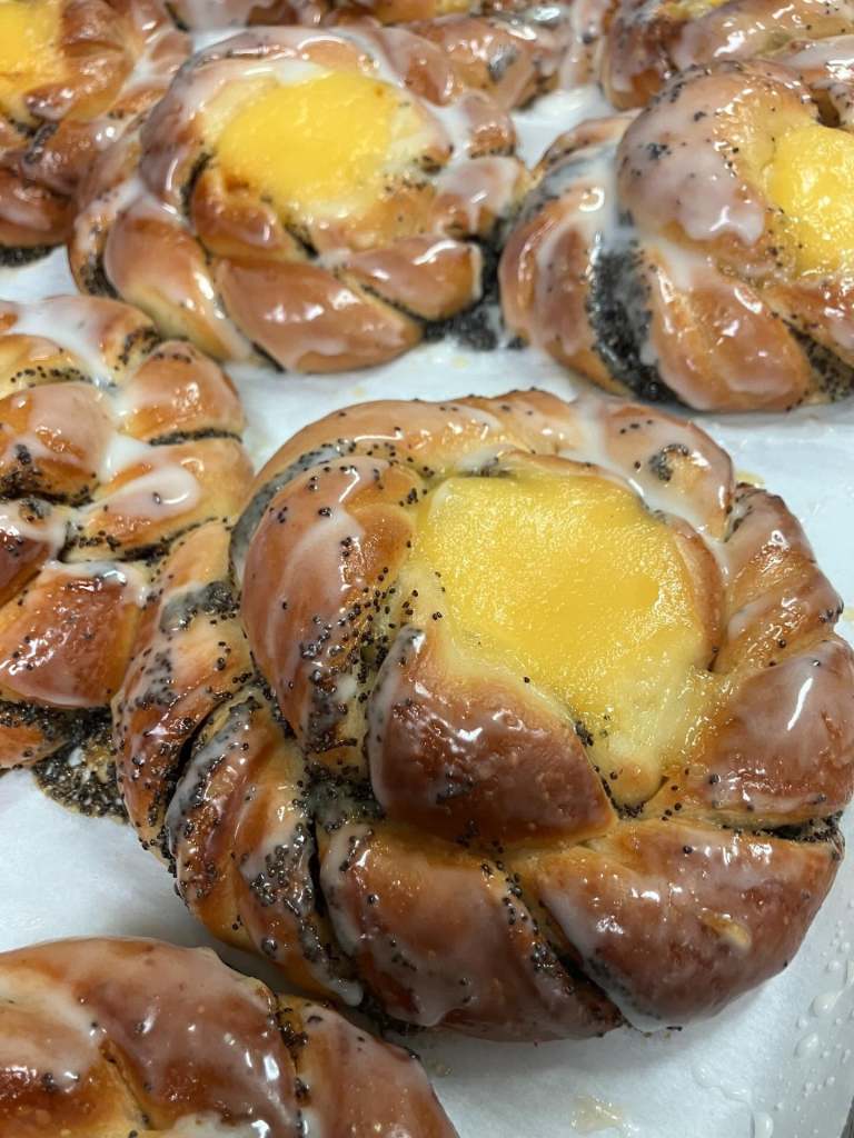 Close-up of glazed pastries with yellow custard center and poppy seeds.