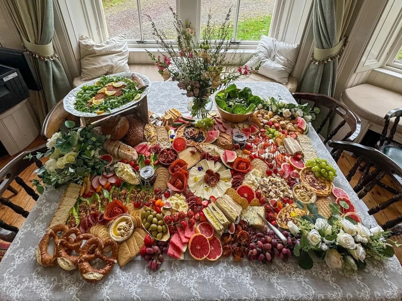 A large, colorful charcuterie spread on a table with meats, cheeses, fruits, vegetables, and breads.