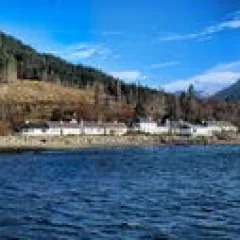 Lakeside village with mountains and blue sky in the background.