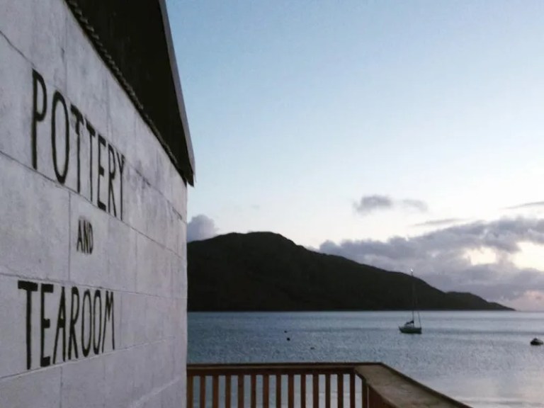 Pottery and tearoom sign by a calm sea at sunset.