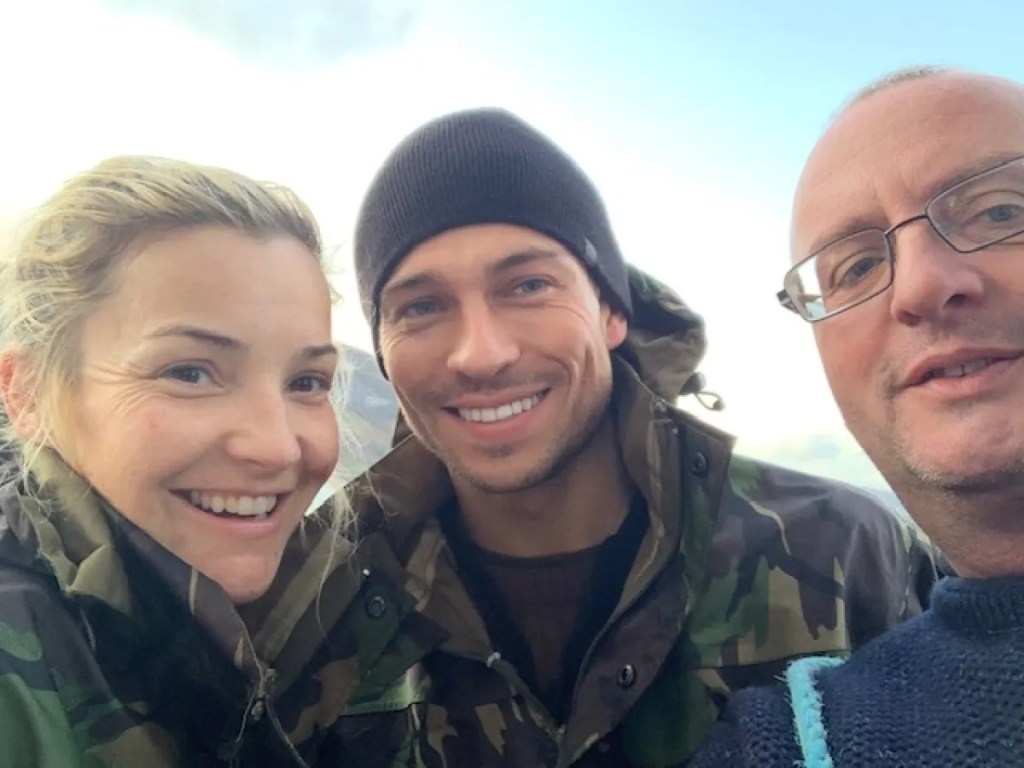 Three people outdoors in jackets, smiling at the camera.