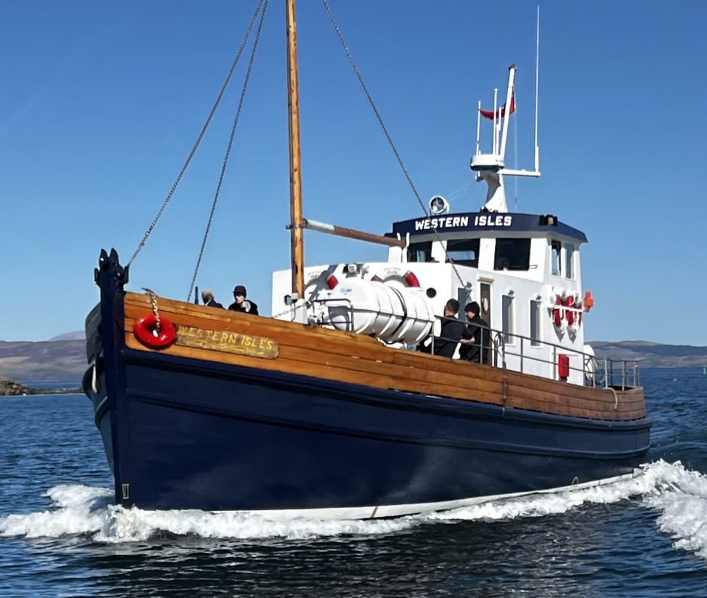 Blue and white boat named 'Western Isles' sailing on calm water.