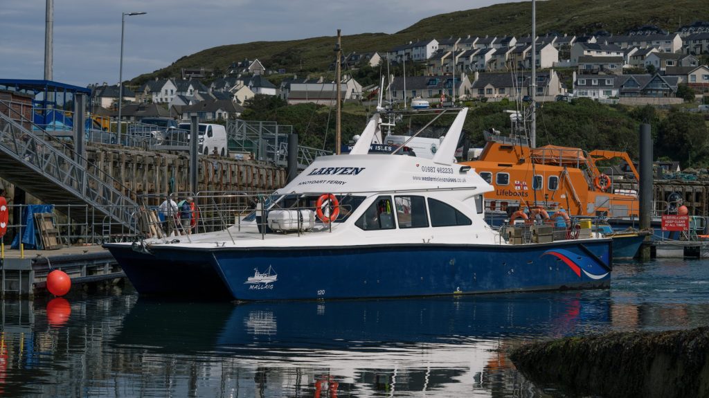 Blue and white boat docked in a harbor beside an orange lifeboat.