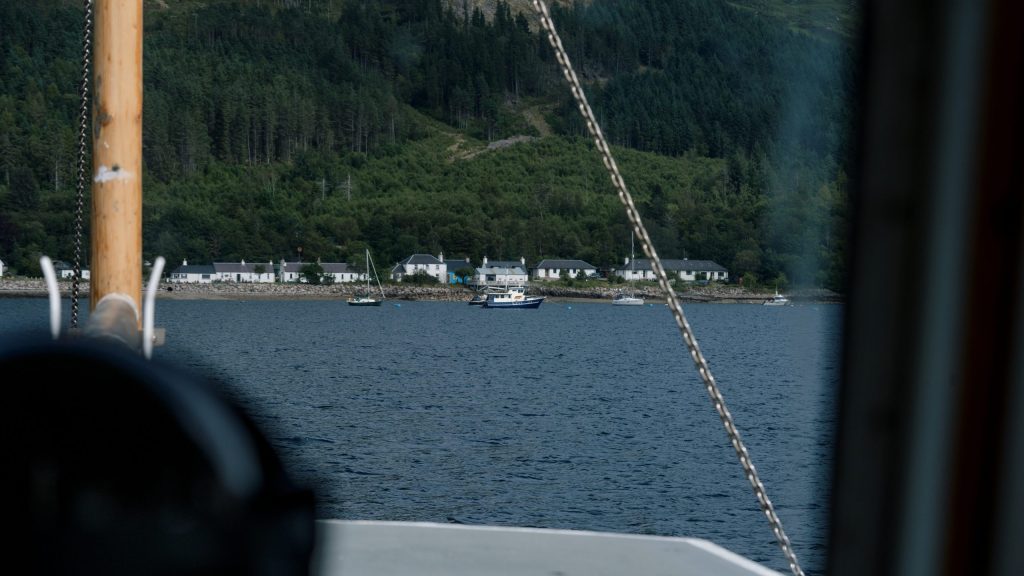 View of a forested shoreline with houses from a boat on the water.