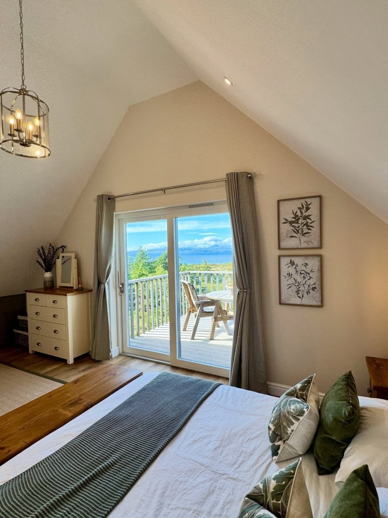 Bedroom with balcony view, double bed, dresser, and large window doors.
