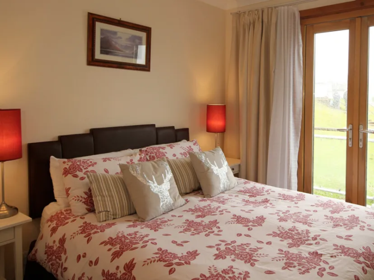 imgi_4_chac Cozy bedroom with red floral bedding, bedside lamps, and glass doors.
