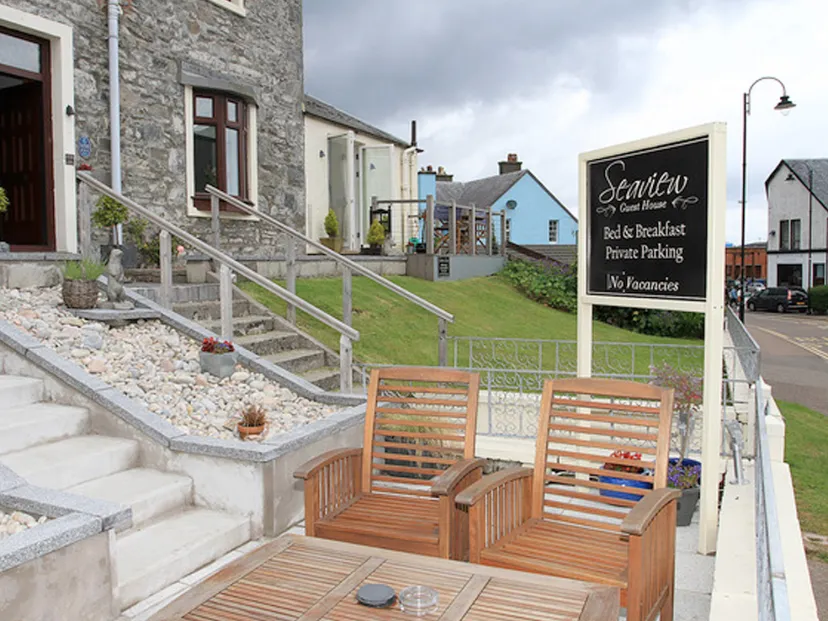 imgi_4_seaview Guest house exterior with sign, seating, and gravel path.