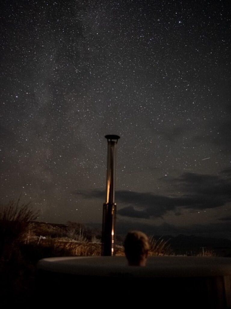 Person in a hot tub under a starry night sky.