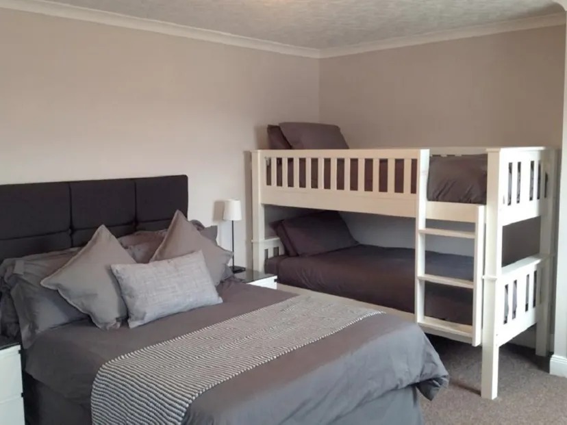 imgi_7_Untitled-1 Bedroom with a double bed and white bunk beds, all with gray bedding.
