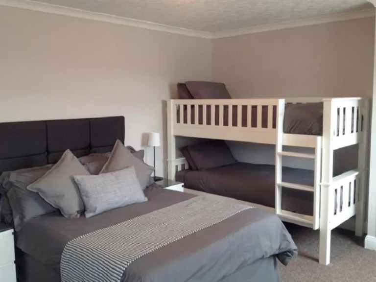 imgi_7_Untitled-1 Bedroom with a double bed and white bunk beds, all with gray bedding.
