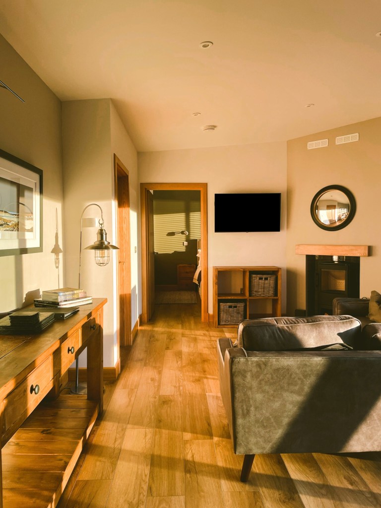 Cozy living room with sofa, TV, and wooden furniture in warm lighting.