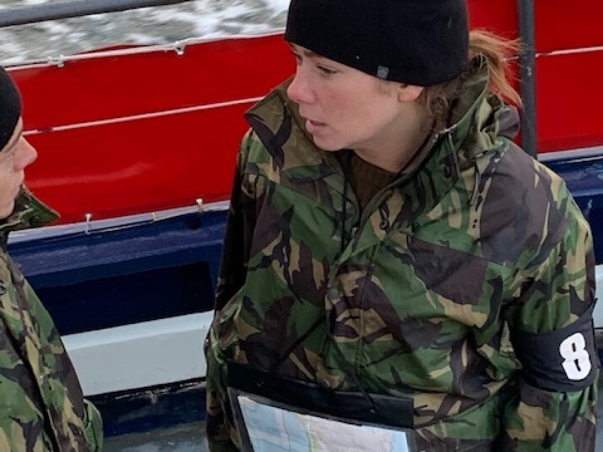 a person in a green uniform sitting on a boat
