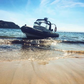 a boat sitting on top of a sandy beach next to the ocean